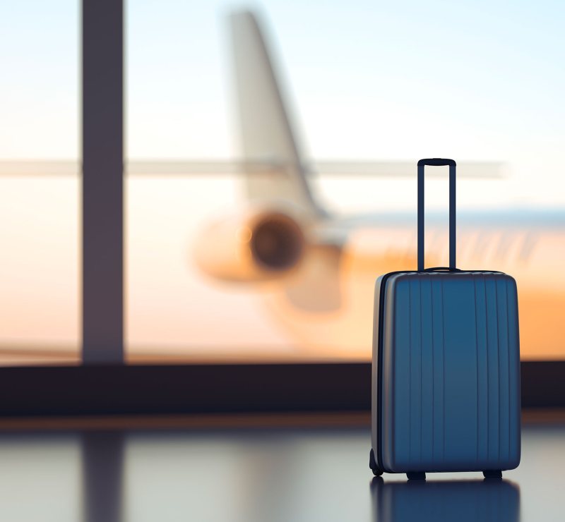 Suitcase at an airport departure gate at sunset